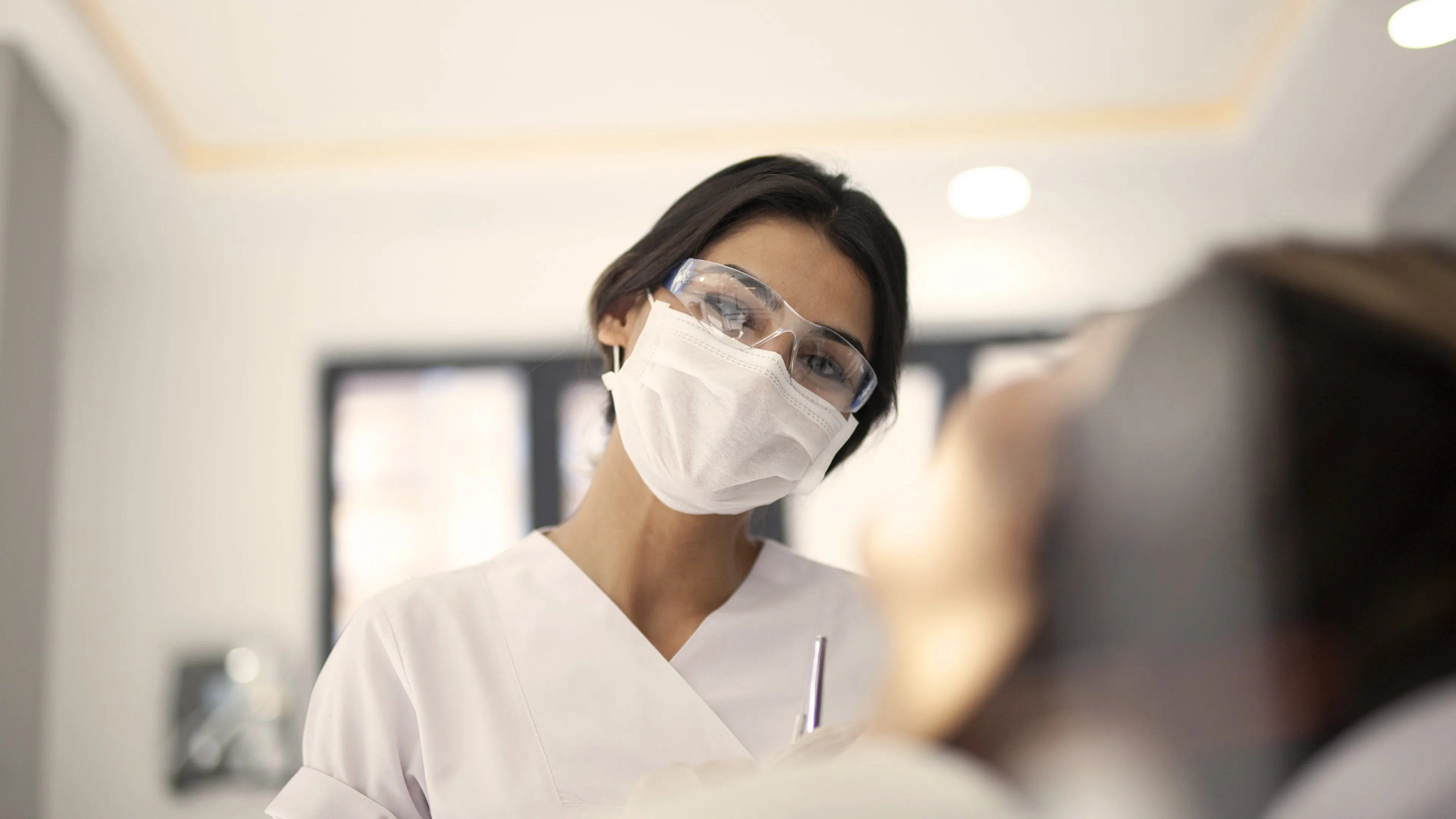 Dental assistant with mask on smiling at patient